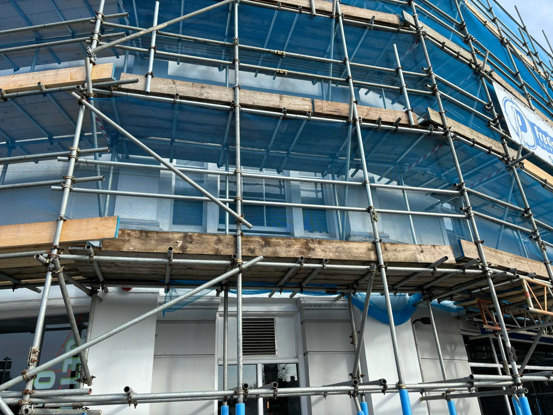Close-up of scaffolding and blue protective sheeting during the painting process