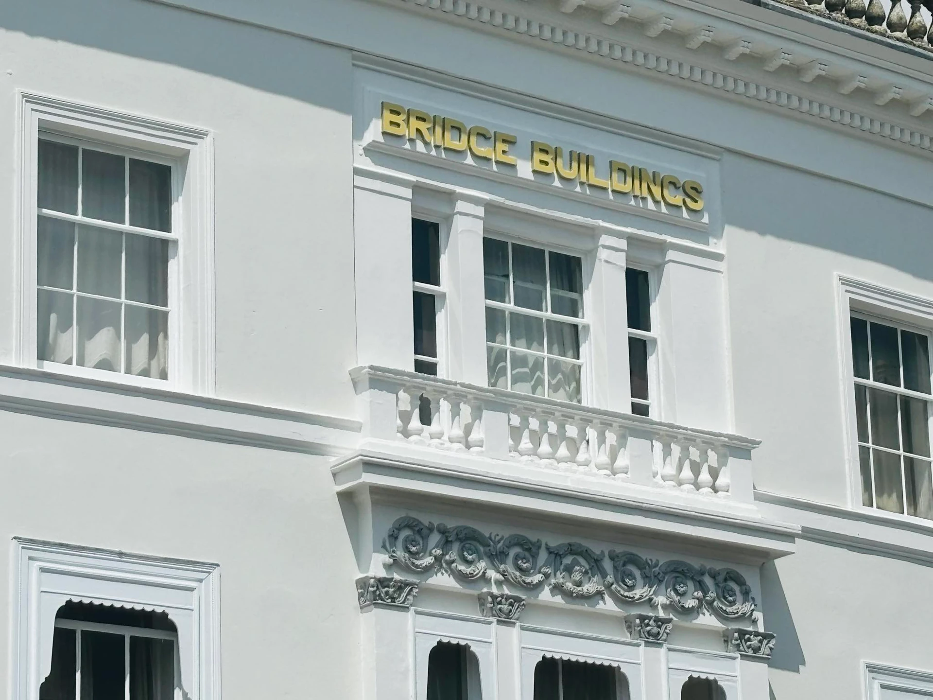 Close-up of the gold 'BRIDGE BUILDINGS' lettering on the white facade