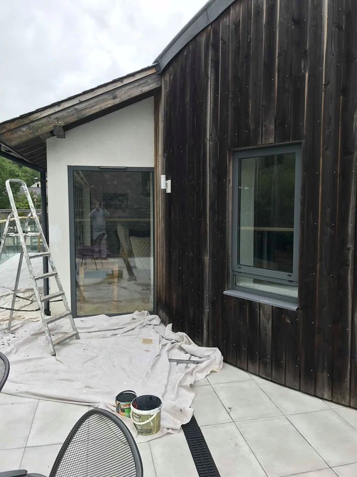 The Fernery exterior during renovation showing dark wooden cladding and glass doors
