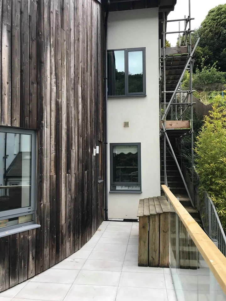 Side view of The Fernery showing wooden cladding, white walls and tiled patio