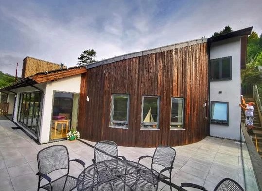 The Fernery exterior showing curved wooden cladding, white walls and outdoor seating area