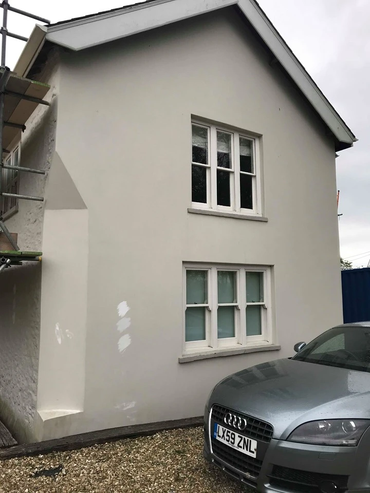 Gray house exterior with white windows and silver Audi car parked beside it