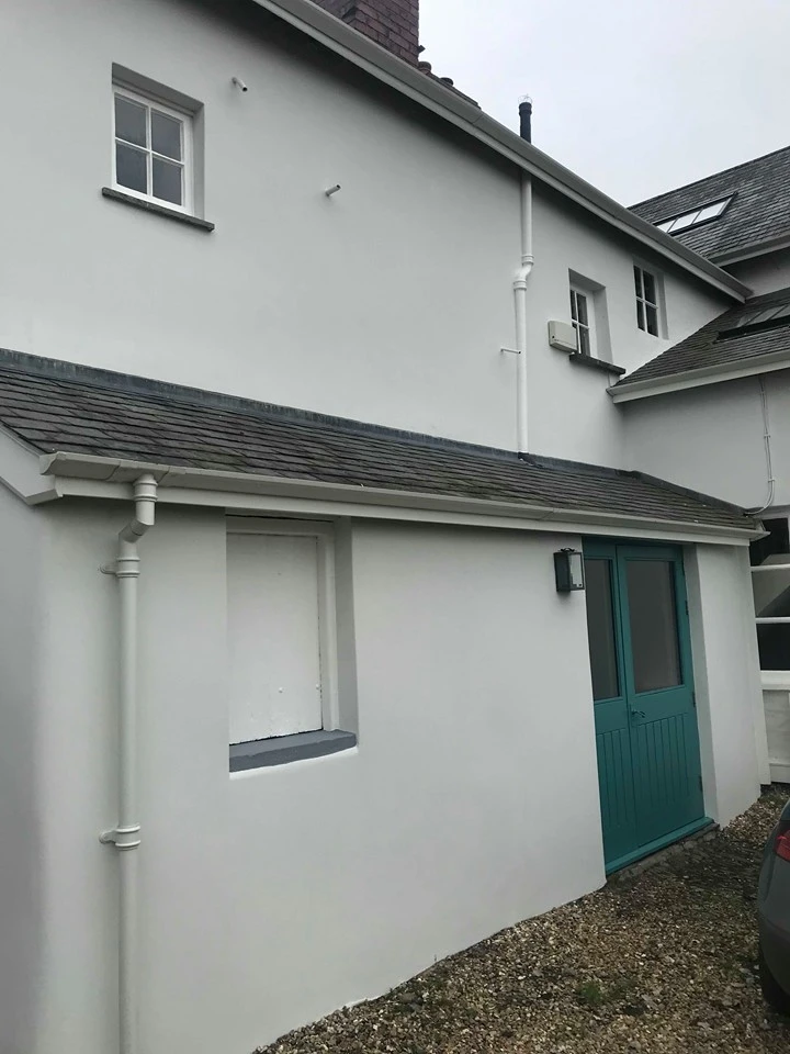 White house exterior with teal door, gray roof and white downpipes