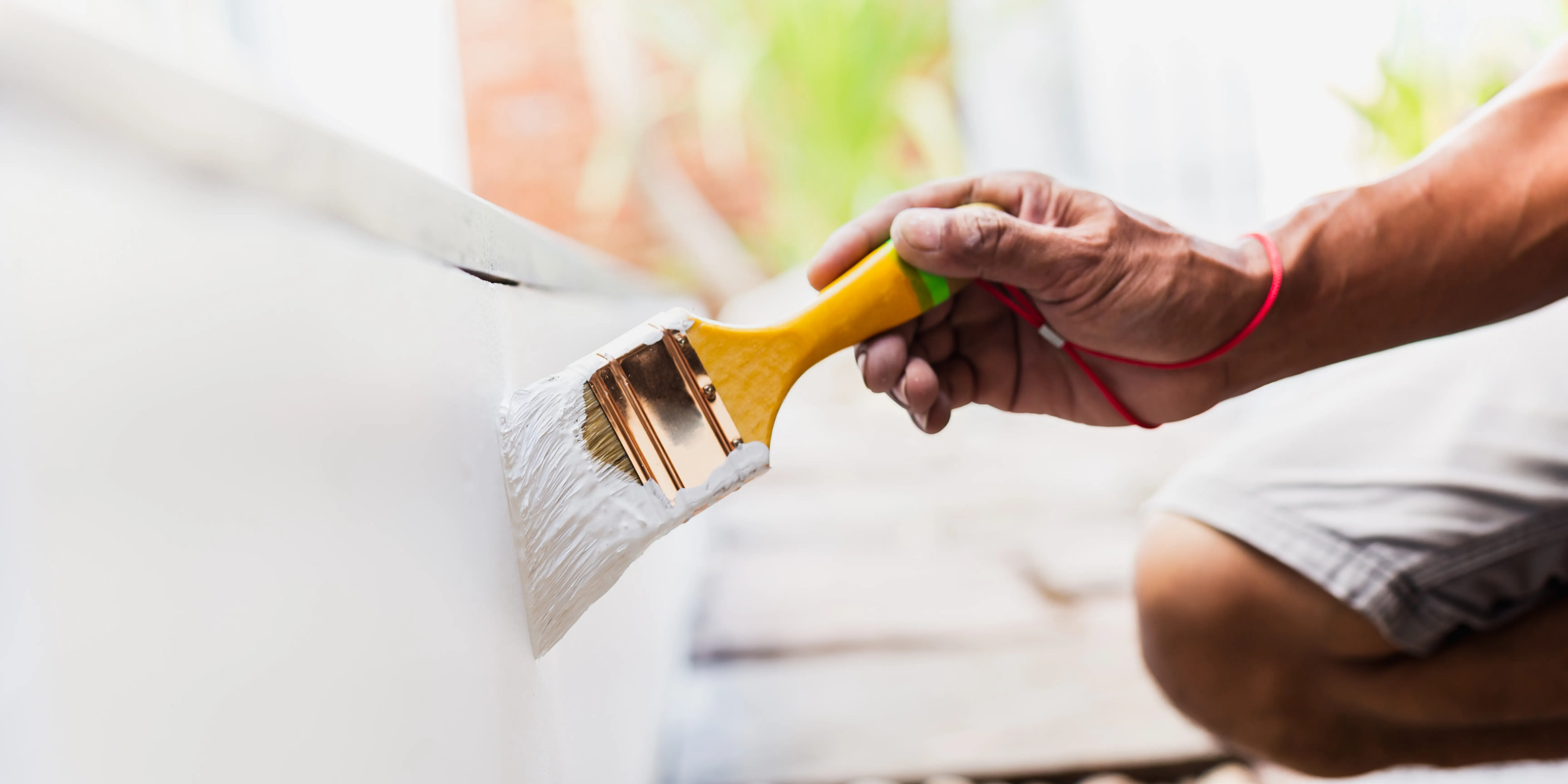 Painter applying white paint to interior wall