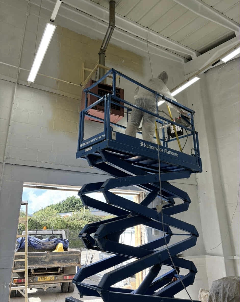 Painter on scissor lift working on walls and ceiling at Parker Hannifin facility
