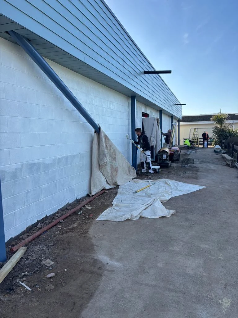Painters working on white walls with blue trim at Ruda Holiday Park