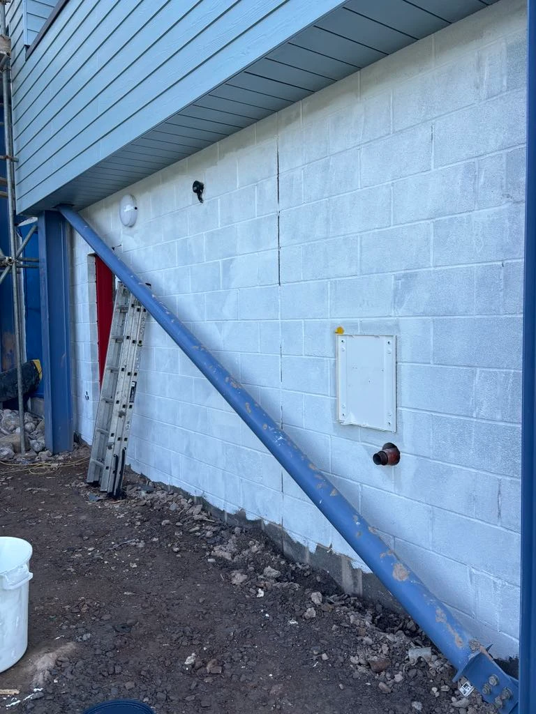 Freshly painted white wall with blue downpipe at Ruda Holiday Park