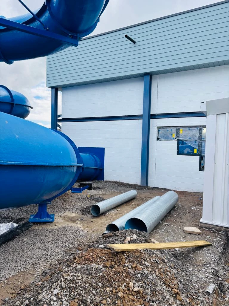 Blue water slide components and metal pipes near freshly painted walls at Ruda Holiday Park