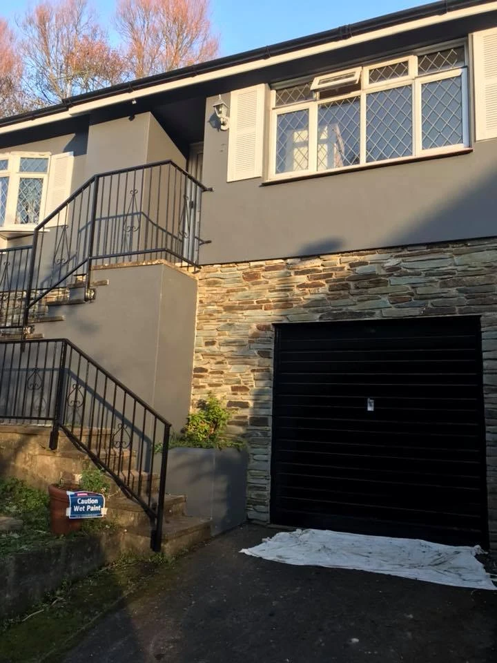 House exterior with gray painted walls, stone cladding and white windows