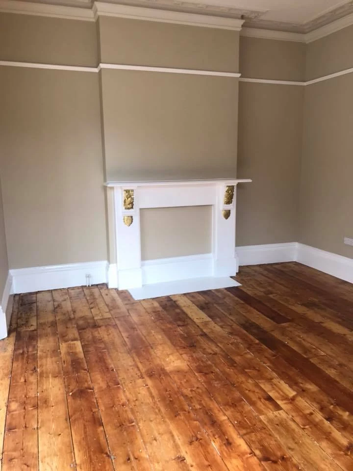 Freshly painted room with beige walls, white trim and wooden flooring