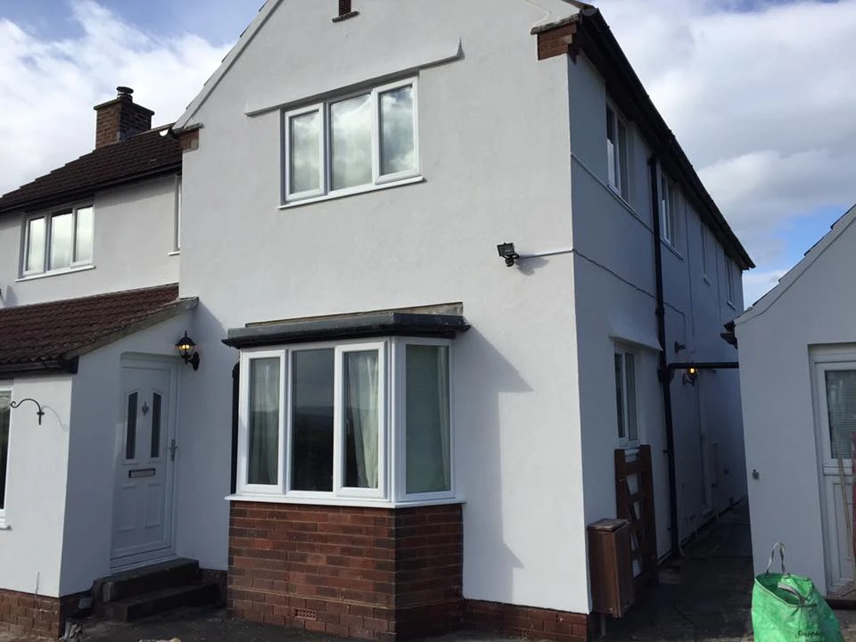 White rendered house with brick base and white windows