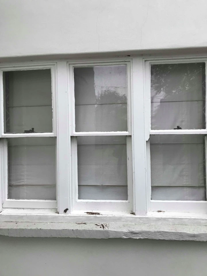 Detailed view of three white sash windows on a white wall with white windowsill