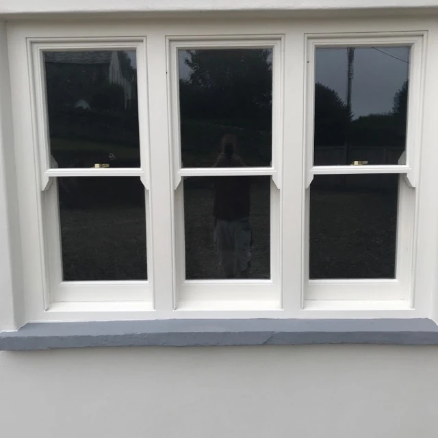White painted sash windows on rendered wall with gray windowsill